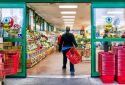 Entrance and exit Reston, USA - December 18, 2017: Trader Joe's customer trolley shopping basket carrying carts by store entrance doors outside women, winter flower pots, gardening plants, pineapple in Virginia